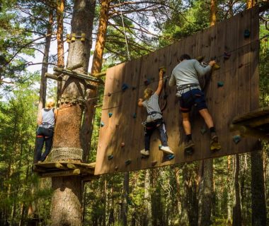 Family enjoying an outdoor climbing adventure in Cercedilla, Madrid amidst lush greenery.
