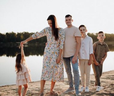 A family of five enjoys a serene lakeside vacation at sunset, capturing precious moments together.